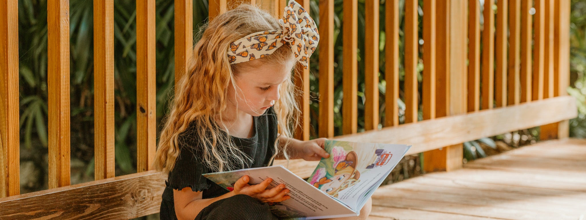 Young girl reading a book on a wooden deck