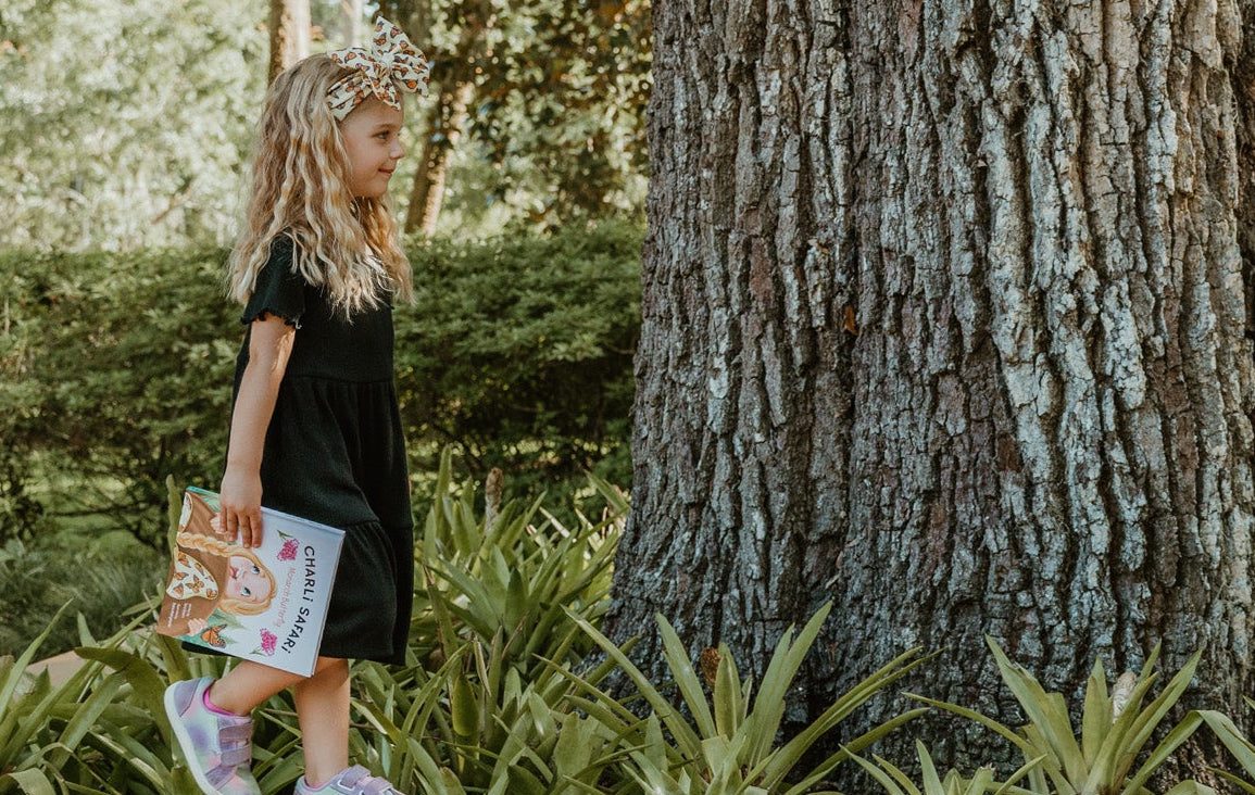 girl walking near a large tree in a park-like setting